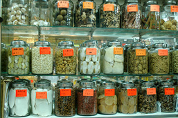Display of various organic products, placed in labeled glass jars and aligned in three rows.